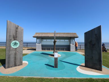 A coastal viewing area with informational wooden panels and a shelter by the sea at 12 Siesta Mar in Mundesley