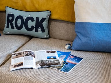 A beige sofa with folded brochures and two decorative cushions at The Snug in St Minver