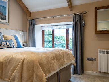 A bedroom with a bed near a window with curtains and a decorative bird at The Snug in St Minver
