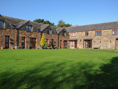Stone cottages with slate roofs and green lawn in front at The Snug in St Minver
