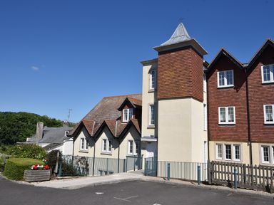 A residential building with cream and brown exterior walls and a tower structure under a clear blue sky at 1 Buckfields in Lyme Regis