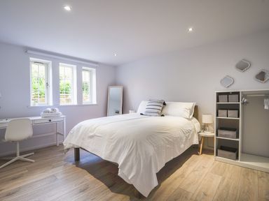 A bedroom with a bed desk chair mirror and open wardrobe at 1 Buckfields in Lyme Regis