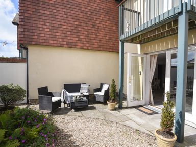 A small outdoor patio with a seating area and plants at 1 Buckfields in Lyme Regis