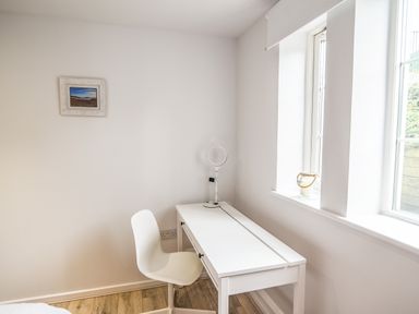 A white desk with a white chair and a ring light next to a window in a room at 1 Buckfields in Lyme Regis