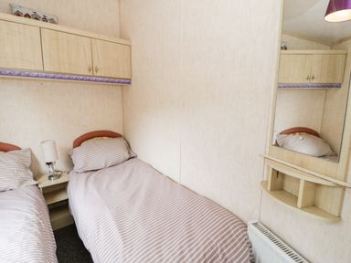 A bedroom with two single beds and wall cabinets at Grange Caravan in Llangollen