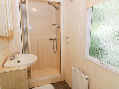 A bathroom with a shower enclosure sink and a window at Grange Caravan Llangollen