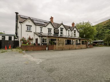 A hotel building with solar panels on the roof and a gravel parking area in front at Grange Caravan in Llangollen