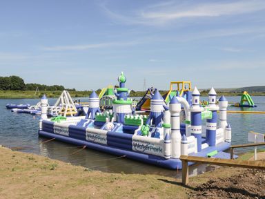 An inflatable water park with castle and slide structures on a lake