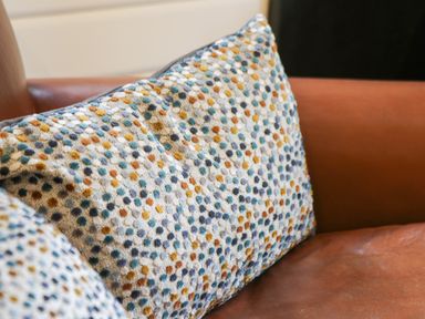 A patterned cushion on a brown leather sofa at Lake View Lodge in Wykeham near East Ayton