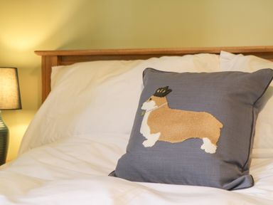 A bed with white bedding and a pillow with a dog design next to a lamp at Lake View Lodge in Wykeham near East Ayton