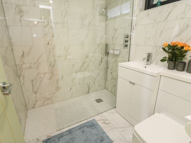 A bathroom with a walk-in shower a white vanity with a sink and orange flowers at Lake View Lodge in Wykeham near East Ayton