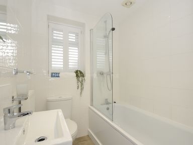 A bathroom with a bathtub shower combination a sink and a toilet at West Cottage in Rock