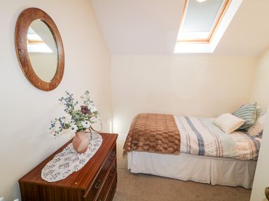 A bedroom with a bed and a dresser with a vase and flowers at 4 The Cloisters in Bushmills County Antrim