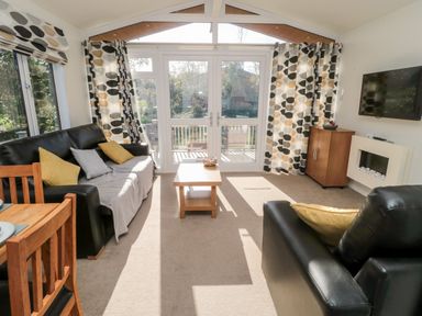 A living room with black leather sofas and a wooden coffee table at Pinecone Lodge - No 9 in Felmoor Park near Felton
