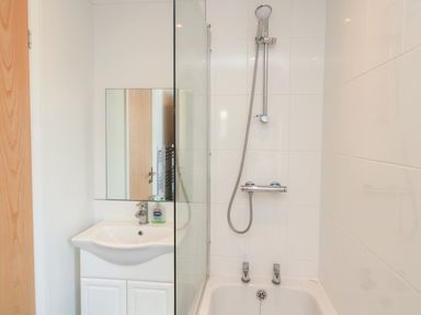 A bathroom with a sink cabinet mirror showerhead and bathtub at Pinecone Lodge - No 9 Felmoor Park near Felton