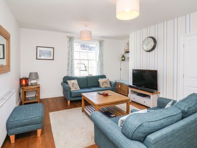 A living room with blue sofas wooden coffee table and television at Navigators Rest in Whitby