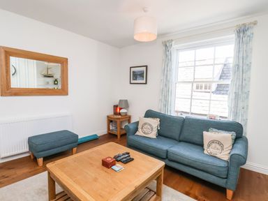 A living room with a blue sofa and ottoman a wooden coffee table and a window at Navigators Rest in Whitby