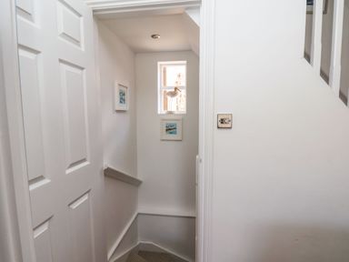 A narrow stairwell with white walls and a small window with a bird decoration at Navigators Rest in Whitby