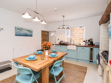 A kitchen with a wooden dining table set with blue bowls and plates and light blue chairs at Navigators Rest in Whitby