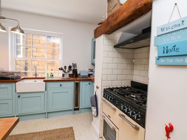 A kitchen with light blue cabinets a stove a sink and a wooden countertop at Navigators Rest in Whitby