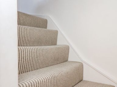 A staircase with beige and white striped carpet at Navigators Rest in Whitby