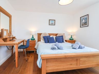 A bedroom with a wooden bed with blue pillows and rolled towels on light blue bedding at Navigators Rest in Whitby