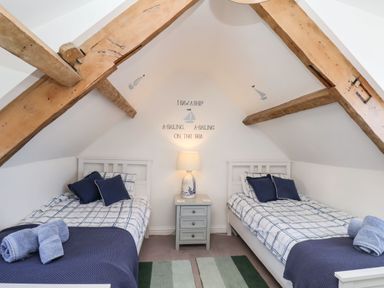 A bedroom with two single beds and a nightstand between under wooden ceiling beams at Navigators Rest in Whitby