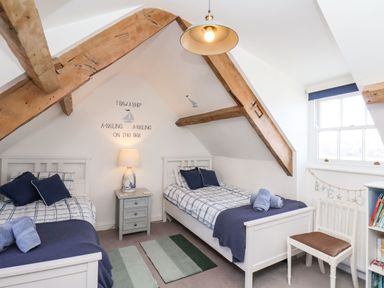 A bedroom with two single beds blue and white bedding wooden beams and a lamp on a bedside table at Navigators Rest in Whitby