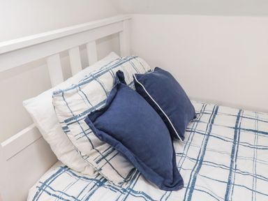 A bed with white and blue checkered bedding and two blue pillows at Navigators Rest in Whitby