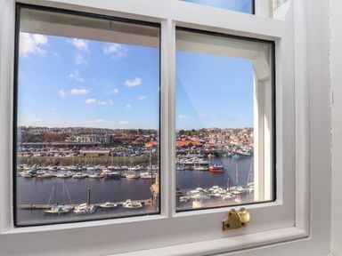 A harbor with boats and buildings viewed through a window at Navigators Rest in Whitby