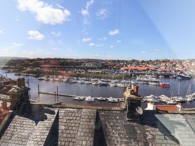 A marina with many boats docked and a town with buildings in the background viewed over rooftops at Navigators Rest Whitby