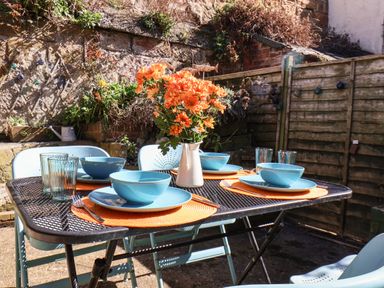An outdoor dining table with blue plates bowls glasses and orange flowers in a vase at Navigators Rest in Whitby