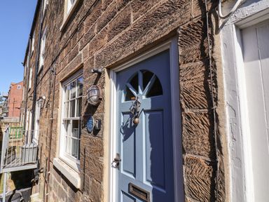 The exterior of a stone building with a blue door and white-framed windows at Navigators Rest Whitby