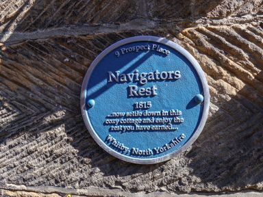 A blue plaque on a textured stone wall with text about Navigators Rest at Whitby North Yorkshire
