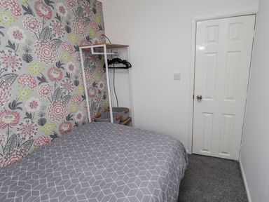 A bedroom with a bed a clothes rack and a door at 19 Cherry Park in Chapel St Leonards