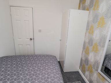 A bedroom corner with a bed a white wardrobe and a door at 19 Cherry Park in Chapel St Leonards