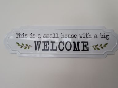 A wall sign with text welcoming to a small house with a big welcome at 19 Cherry Park in Chapel St Leonards