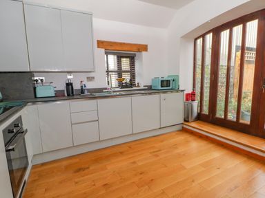 A kitchen with cabinets countertop appliances wooden floor and glass doors at Burnt Oak Stables in Mynydd Isa