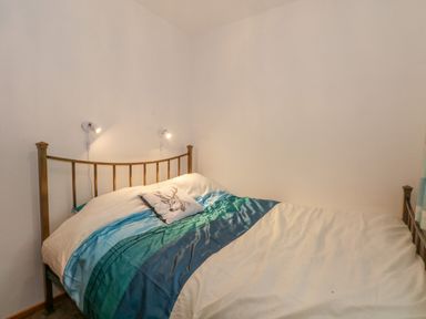 A bedroom with a bed with blue and white bedding and a metal headboard at Burnt Oak Stables in Mynydd Isa