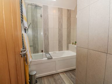 A bathroom with a bathtub shower combination towels on a rail and small plants on the bathtub at Burnt Oak Stables in Mynydd Isa