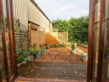 A garden with potted plants wooden fence and a bench at Burnt Oak Stables in Mynydd Isa