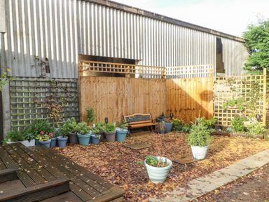 A garden area with potted plants a wooden bench and lattice fencing at Burnt Oak Stables in Mynydd Isa