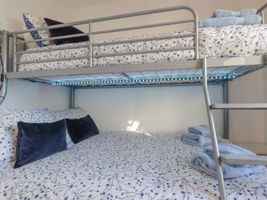 A bunk bed with floral bedding and folded towels in a bedroom at Sea View in Mevagissey
