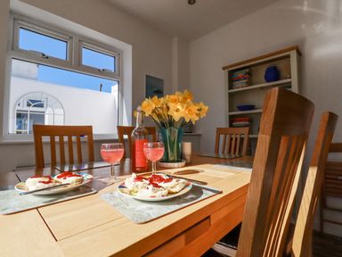 A dining table set with plates of scones with jam and glasses of pink drink in a dining room at Sea View in Mevagissey