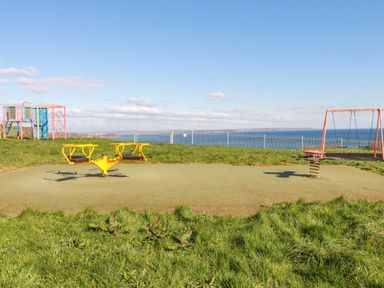 A playground with swings, a seesaw, and climbing equipment near the coast at Sea View in Mevagissey