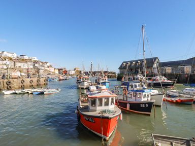 A harbor with boats docked and buildings along the shore at Sea View in Mevagissey