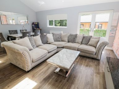 A living room with a large sectional sofa and a marble coffee table at Lodge 32 in Otterburn
