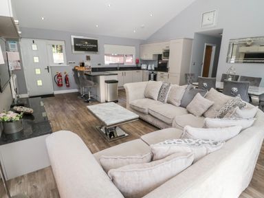 An open plan living room and kitchen with a beige sofa and marble coffee table at Lodge 32 Otterburn