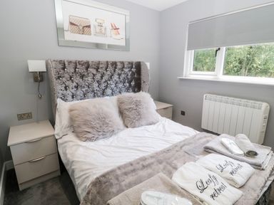 A bedroom with a double bed fluffy pillows bedside tables and a window at Lodge 32 in Otterburn