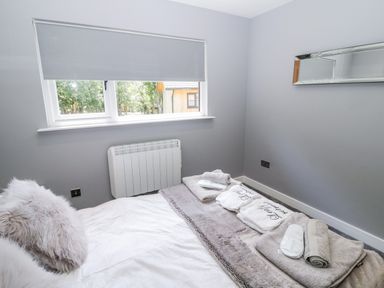 A bedroom with a bed and towels on it under a window with a blind at Lodge 32 in Otterburn